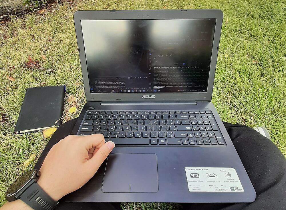 Laptop on a lap in the university campus green space, running CS50 problem set checks